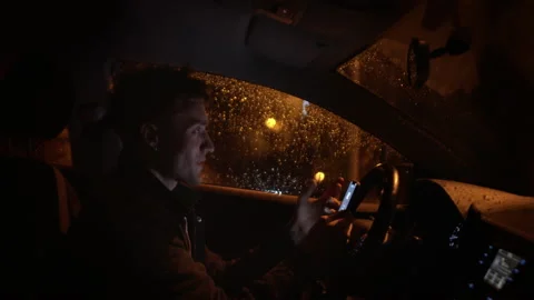 Handsome young man hides from the rain and speaks with somebody with smartphone Stock Footage 150689480