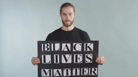 Handsome young man hold poster Black Lives Matter on grey background racial Stock Footage 133637599