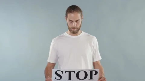 Handsome young man hold poster Stop Racism look at camera serious racial Stock Footage 133639079