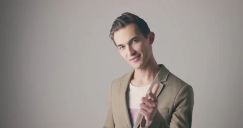 Handsome young man in a jacket isolated over grey wall background showing call Stock Footage 147998332