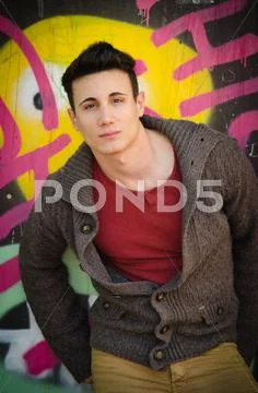 Handsome young man leaning against graffiti wall Stock Photos