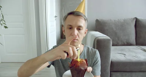 Handsome young man lighting one candle on a cake and looking at the camera Stock Footage 130189927