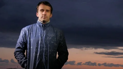 Handsome young man looking at the camera at sunset on the field. Beautiful sky Stock Footage 76992205