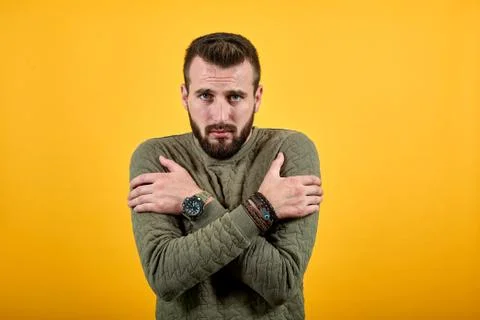 Handsome young man looking at camera, keeping hand crossed, hugging himself Stock-Fotos