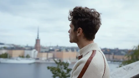 Handsome young man looking out over Stockholm City, turns and looks at camera in Stock Footage 115554978