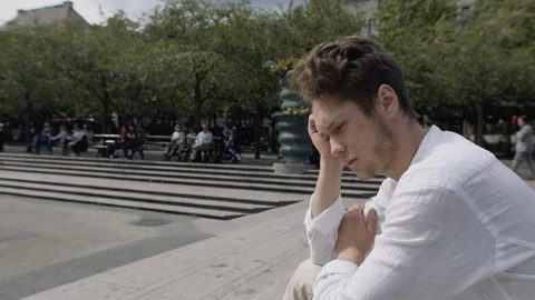 A handsome young man looking sad and concerned in a city square. Vidéo 115984946