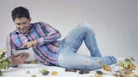 Handsome young man lying and studying on tablet over white background 動画素材 42674604
