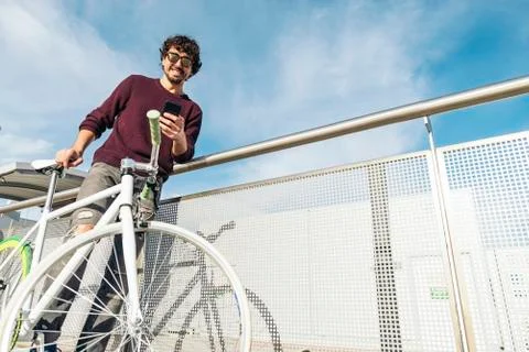 Handsome young man with mobile phone and fixed gear bicycle. Stock Photos