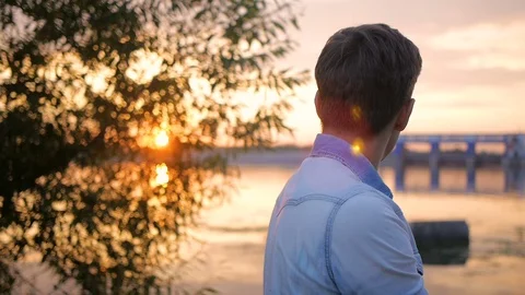 Handsome young man model posing on the lake at sunset Video stock 72838248