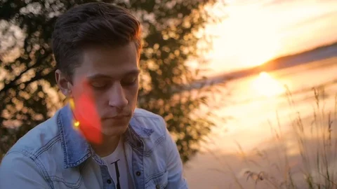 Handsome young man model posing on the lake at sunset Video stock 72838806
