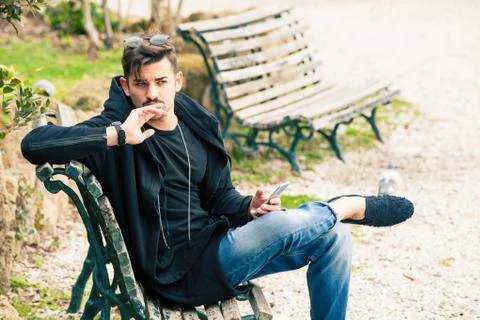 Handsome young man model sitting on the bench. A handsome young man is sittin Stock Photos