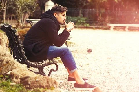 Handsome young man model sitting on the bench. A handsome young man is sittin Stock Photos