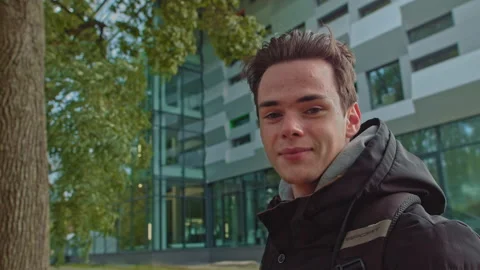 Handsome young man in modern warm clothes with a backpack on his shoulders looks Stock Footage 141708967