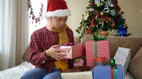 Handsome young man opening his Christmas gift Stockbeeldmateriaal 81936236