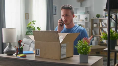 A handsome young man opens a parcel in which lies the trash. He calls the 스톡 동영상 133565266