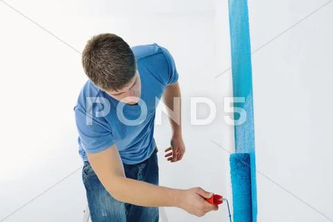 Handsome young man paint white wall in color Stock Photos