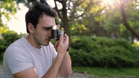 Handsome young man in park taking photos with analog camera Stock Footage 87388351