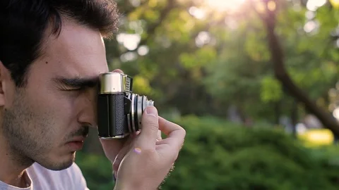 Handsome young man in park taking photos with analog camera Stock Footage 87388576