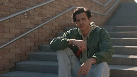 Handsome young man with piercing in ear sitting on stairs Stock Footage 163910191