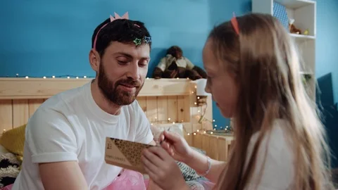 Handsome young man plays with her daughter while sitting on bed. Little preteen Stock Footage 112257600