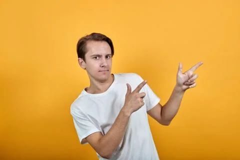 A handsome young man points the direction with his fingers in white t-shirt Stock Photos