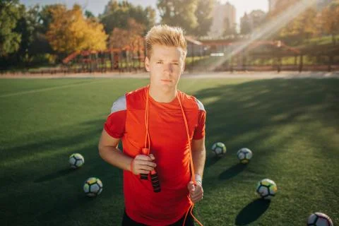 Handsome young man posing on camera. He looks straight and hold jump rope around Stock Photos