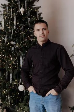 Handsome young man posing in front of Christmas tree Stock Photos