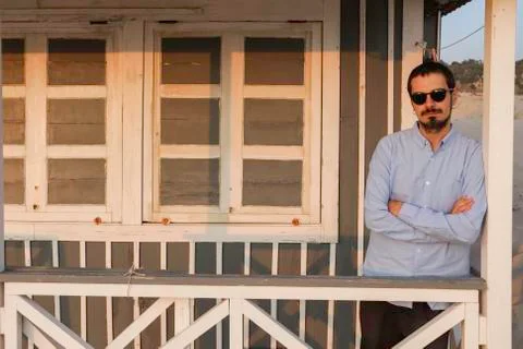 An handsome young man posing under the porch of a typical cottage house along Stock Photos