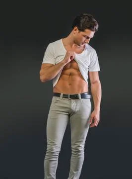 Handsome young man pulling up t-shirt, showing abs Stock Photos