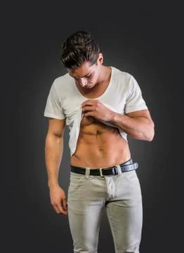 Handsome young man pulling up t-shirt, showing abs Stock Photos