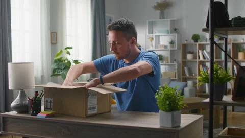 A handsome young man pulls out a portable speaker from a cardboard box Vidéo 133565684