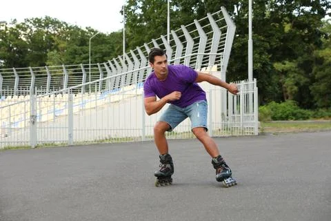 Handsome young man roller skating outdoors. Recreational activity Stock Photos