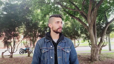 Handsome young man seen from front walking in a forest of a park in the city Stock Footage 248307827