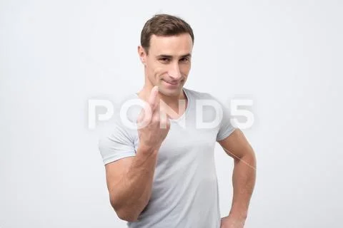 Handsome young man showing come here gesture with index finger and smiling ov Stock Photos