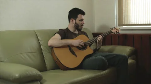 A handsome young man singing and playing the guitar Stock Footage 61884759