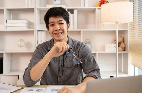Handsome young man sits working at a desk with a laptop and office equipment, Stock Photos