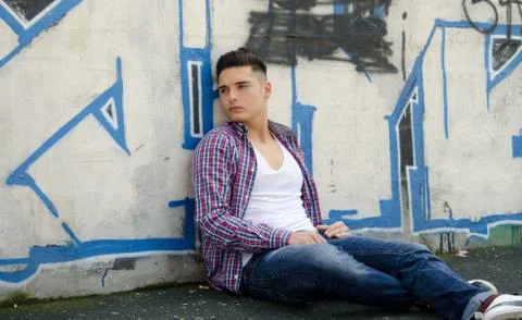 Handsome young man sitting against colorful graffiti Stock Photos