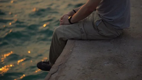 Handsome Young Man Sitting Alone on Dock by Sea Looking at Sunrise Video stock 126259234