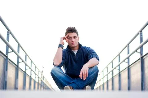 Handsome young man sitting between handrails in walkway Stock Photos