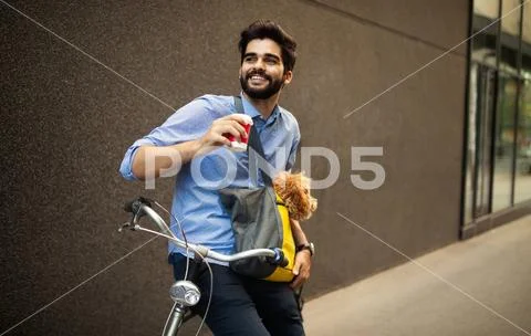 Handsome young man sitting on bike and holding coffee cup on street Stock Photos