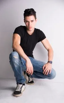 Handsome young man sitting on light background Stock Photos