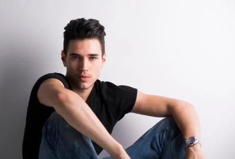 Handsome young man sitting on light background Stock Photos
