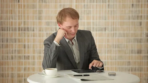 Handsome young man sitting at table using touchpad and smiling at camera Video stock 34279606