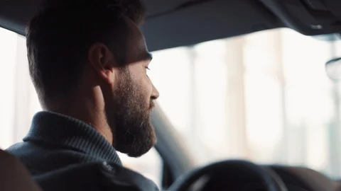 Handsome young man sitting at wheel of car, saying something. Guy spending time Stock-Footage 86174659