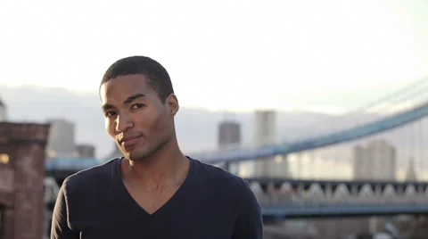 A handsome young man smiles for the camera with a huge city backdrop Stock Footage 34000080
