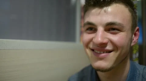 Handsome Young Man smiling happily with interest sitting at a table in a cafe Stock Footage 61012134