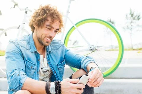 Handsome young man smiling when he is using his mobile. Stock Photos