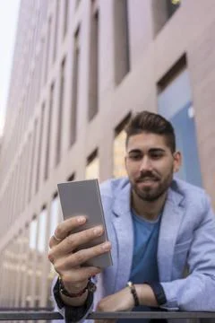 Handsome young man smiling when he is using his mobile phone Stock Photos