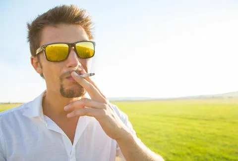 Handsome young man smoking cigarette Stock Photos