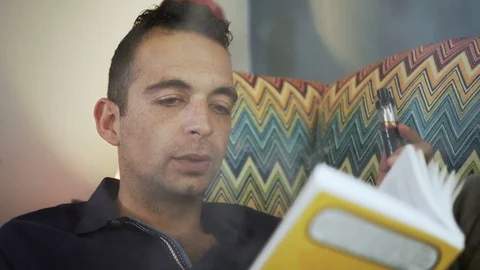 Handsome young man smoking e-cigarette and relaxing at home Stock Footage 80935685